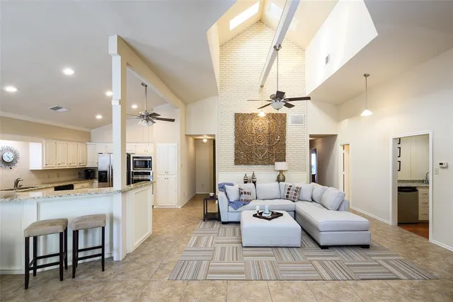 a living room with stainless steel appliances furniture and a kitchen view