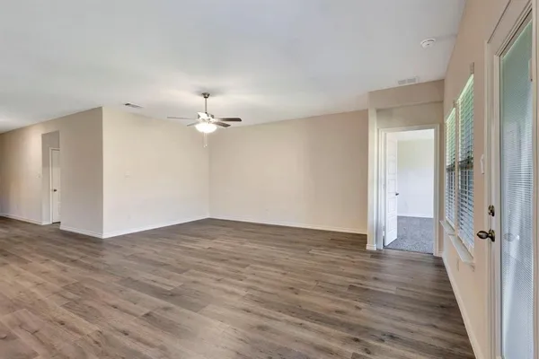 a view of an empty room with wooden floor and a window