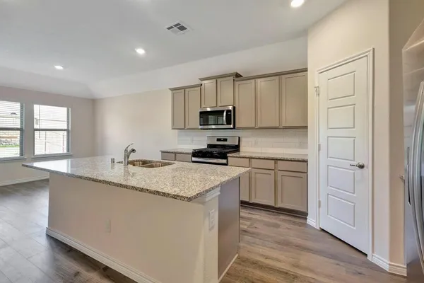 a kitchen with stainless steel appliances granite countertop a sink a stove a refrigerator and cabinets