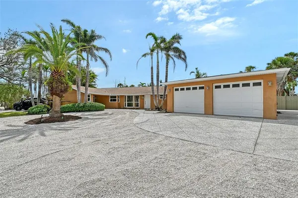 a front view of a house with a yard and palm trees