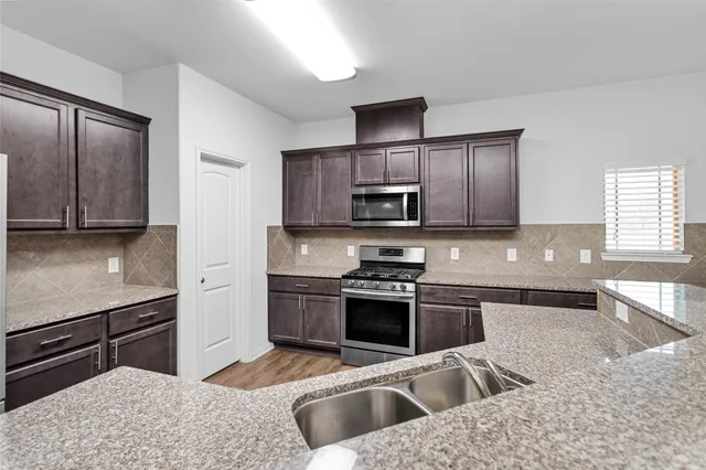 a kitchen with stainless steel appliances granite countertop a sink stove and refrigerator