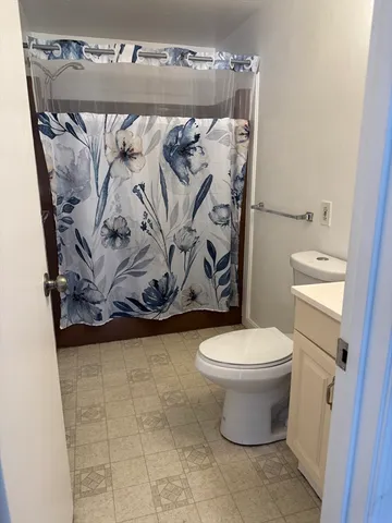 a bathroom with a toilet and a shower curtain