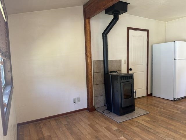 673 Minaret Road June Lake, CA 93529 - Photo 8 of 22 Wood-finish flooring, exposed wood beam, black pellet stove, ceramic tile hearth, white paneled door