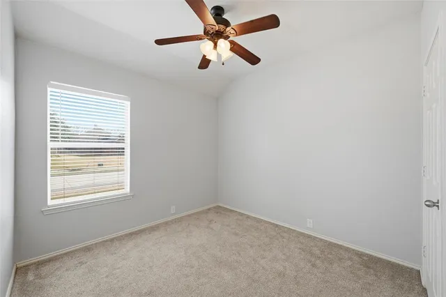 an empty room with a window and a fan