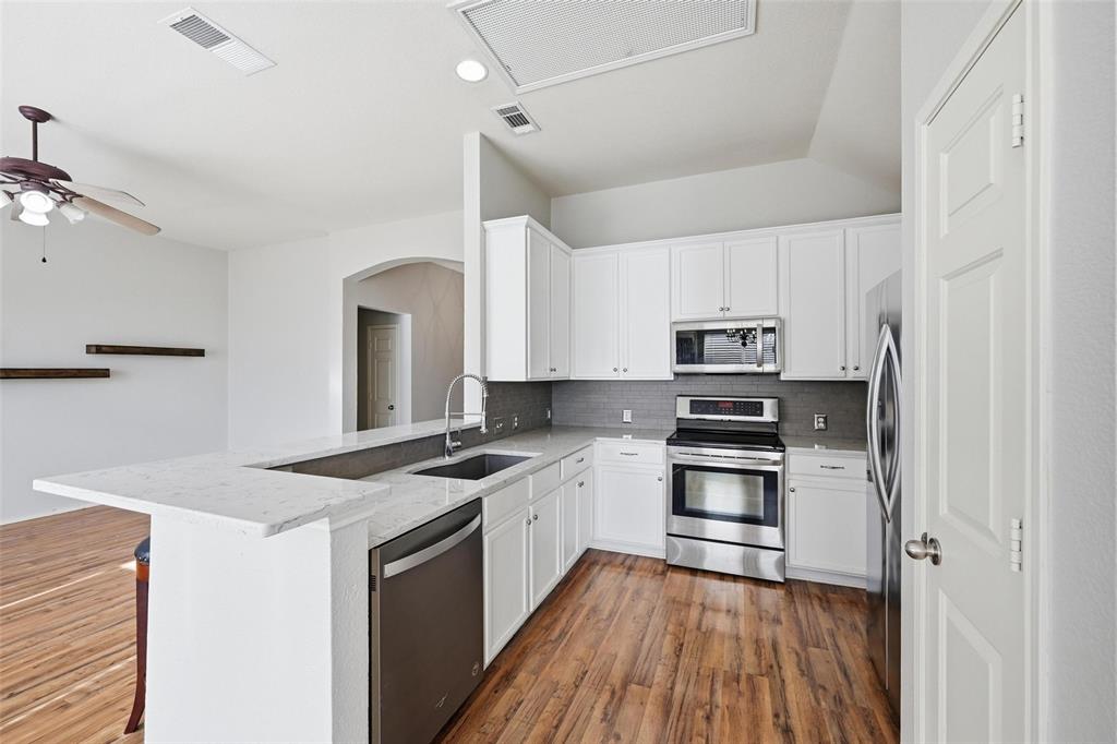 1020 Hay Stack Court Little Elm, TX 75068 - Photo 5 of 20 a kitchen with stainless steel appliances granite countertop a stove top oven a sink dishwasher and a refrigerator with wooden floor