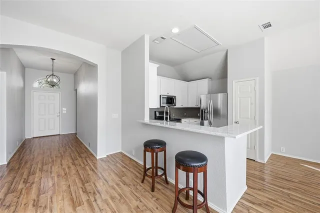 a kitchen with stainless steel appliances a dining table chairs refrigerator and sink