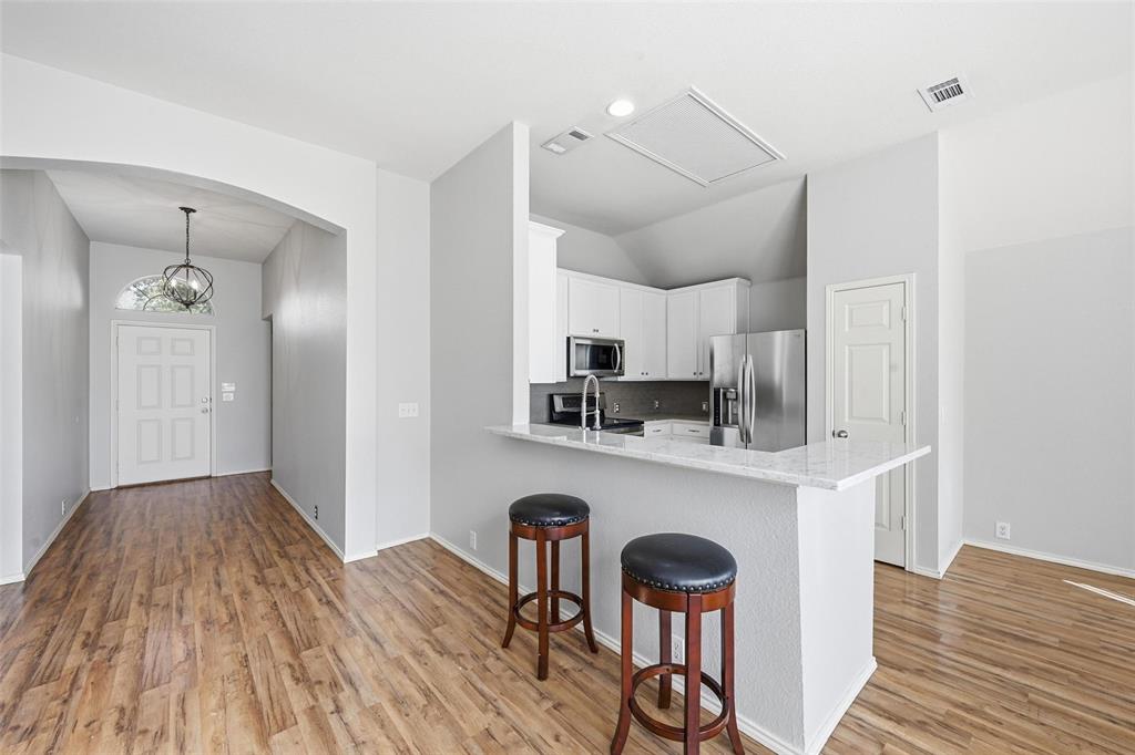 1020 Hay Stack Court Little Elm, TX 75068 - Photo 7 of 20 a kitchen with stainless steel appliances a dining table chairs refrigerator and sink