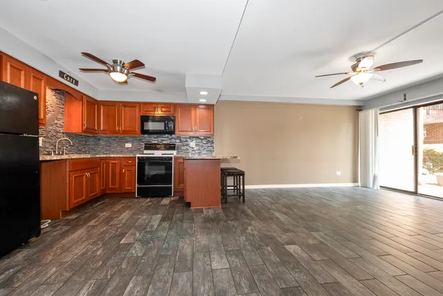 a kitchen with stainless steel appliances granite countertop a stove top oven a chimney cabinets and wooden floor