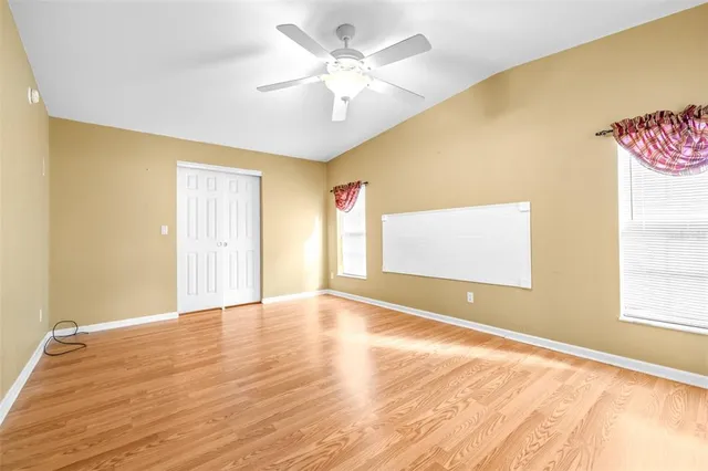 a view of an empty room with window and wooden floor