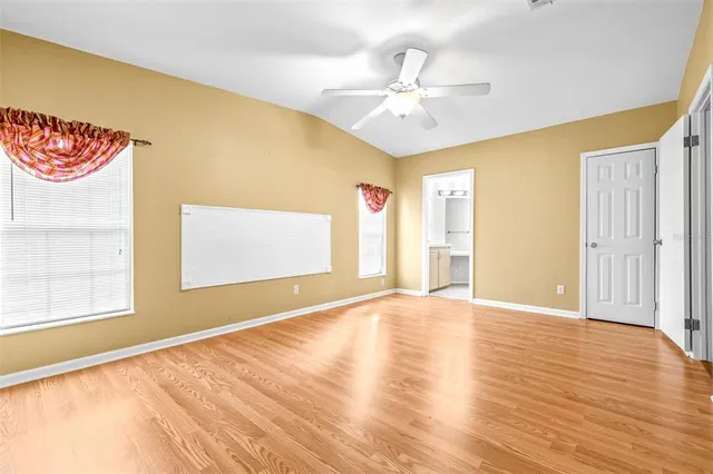 a view of an empty room with window and wooden floor