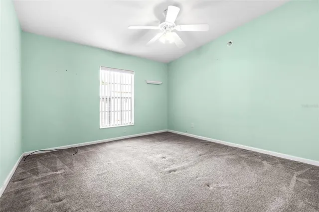 an empty room with windows and ceiling fan