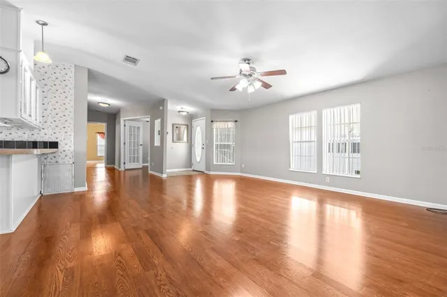 a view of an empty room with wooden floor and a window