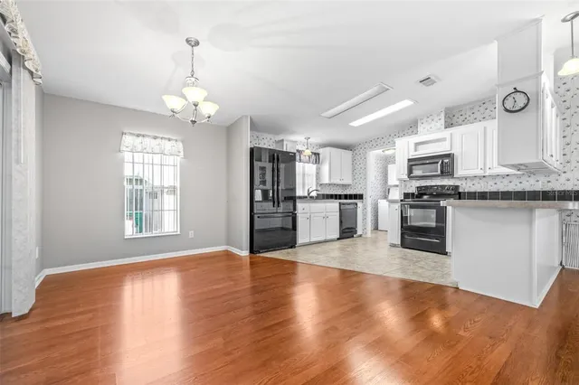 a view of kitchen with granite countertop stainless steel appliances cabinets a sink and a wooden floor