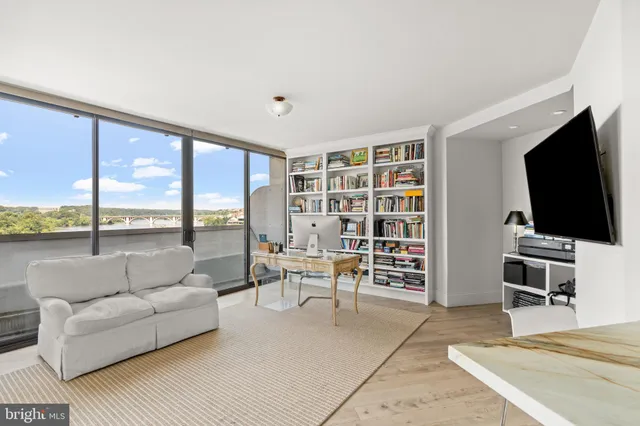 a living room with furniture a flat screen tv and a floor to ceiling window