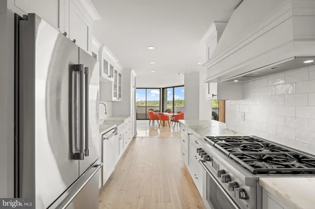a large white kitchen with stainless steel appliances granite countertop a refrigerator and a sink