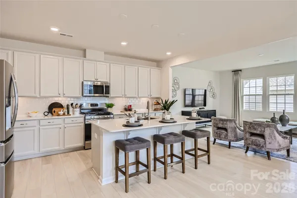 a kitchen with appliances a table and chairs in it