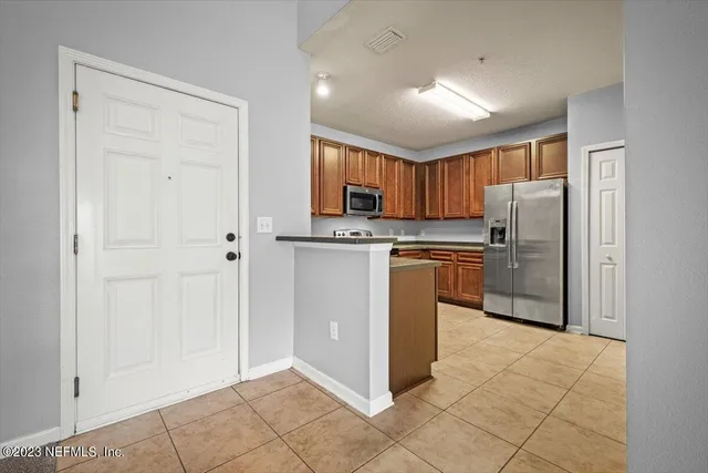 a kitchen with granite countertop a refrigerator sink and cabinets