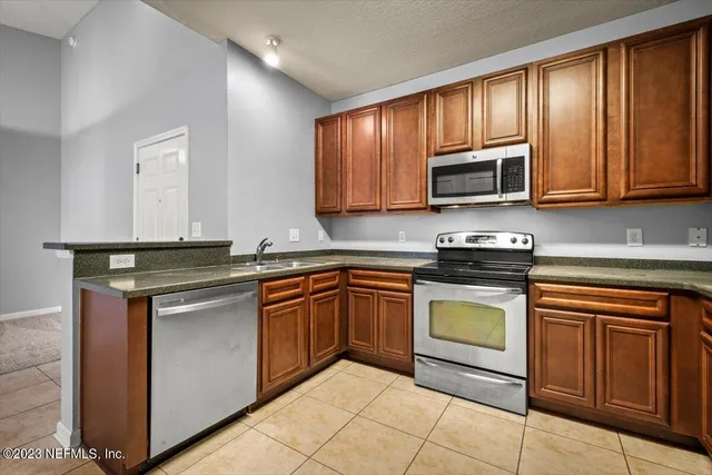a view of a refrigerator in kitchen and an empty room in wooden floor