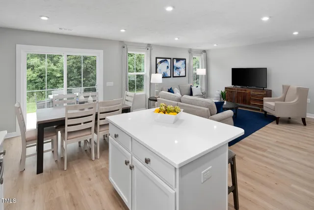 a kitchen with stainless steel appliances granite countertop a dining table chairs refrigerator and microwave