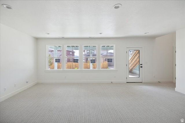 7189 South Sage Road, Unit 214 West Jordan, UT 84081 - Photo 26 of 29 Spacious room featuring light-toned carpet flooring, four windows with white trim, a glass-paneled door, recessed ceiling lighting, and white walls