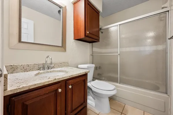 a bathroom with a granite countertop sink a toilet and shower