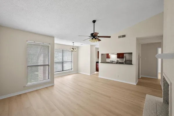 a view of empty room with wooden floor and kitchen view
