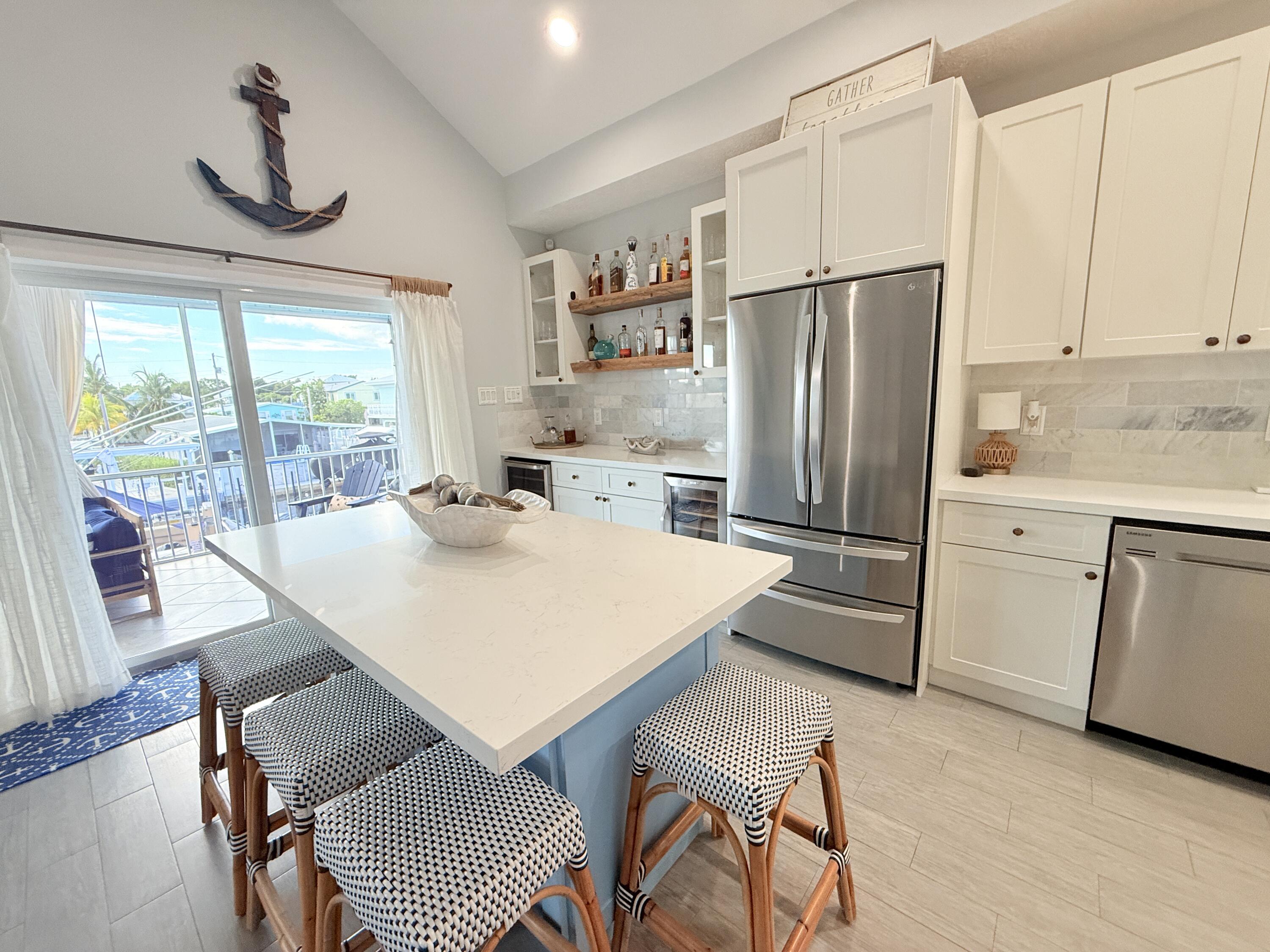 614 R Santa Anita Lane Key Largo, FL 33037 - Photo 16 of 64 a kitchen with stainless steel appliances granite countertop a refrigerator a sink dishwasher a stove a dining table and chairs with wooden floor