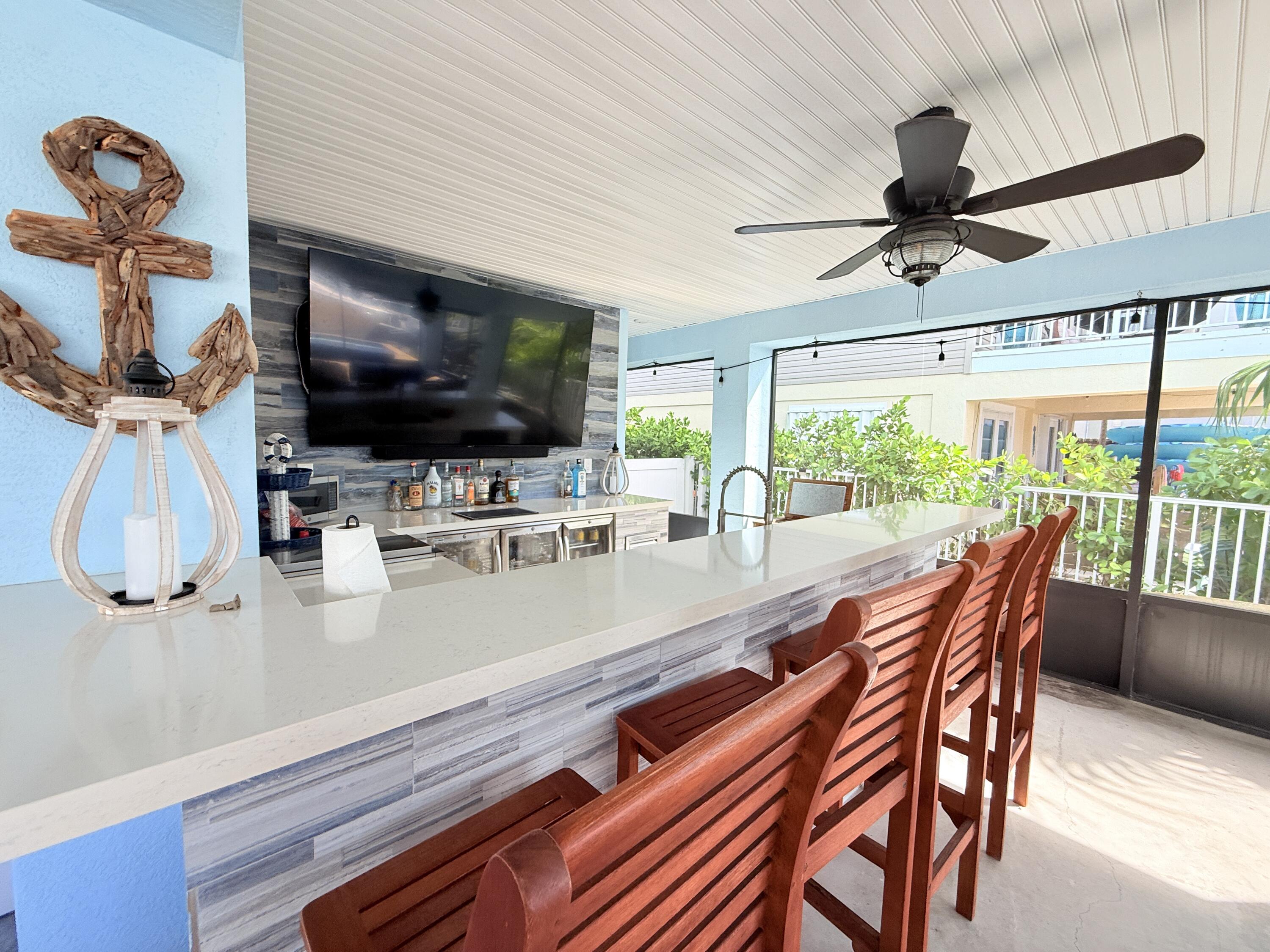 614 R Santa Anita Lane Key Largo, FL 33037 - Photo 46 of 64 a dining room with furniture a flat screen tv and a floor to ceiling window