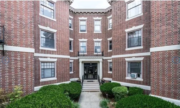 a front view of a brick building with a yard
