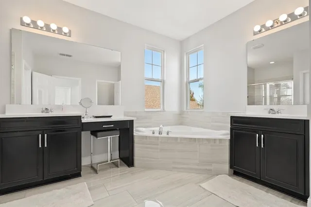 a bathroom with a bathtub sink and double vanity