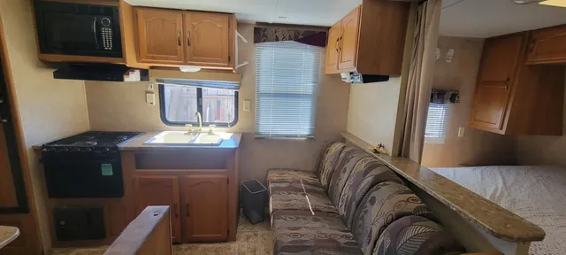 a living room with stainless steel appliances furniture a refrigerator and a cabinets