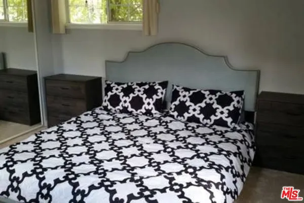 a bedroom with a bed and a lamp next to a window