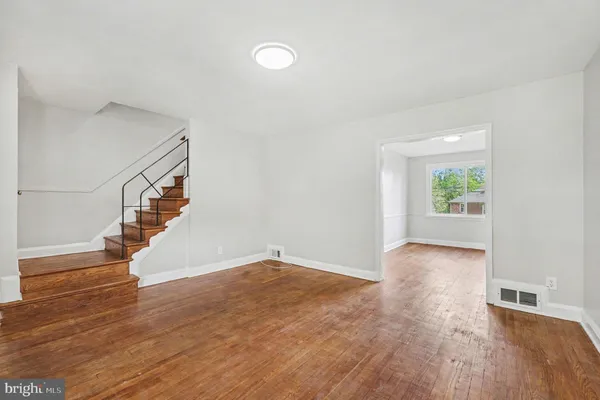 a view of an empty room with wooden floor and stairs
