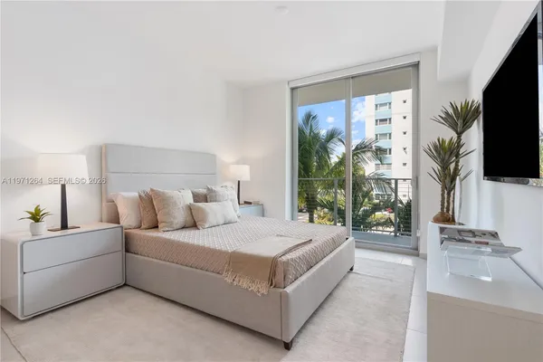 a bedroom with a large bed and a flat tv screen on dresser