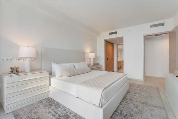 a bedroom with a bed and a lamp on dresser