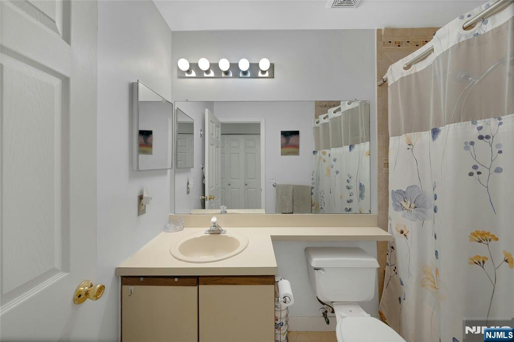 72 Marrow Street, Unit 3101 Newark, NJ 07103 - Photo 18 of 20 a bathroom with a sink a toilet a mirror and shower curtain