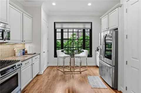 a kitchen with stainless steel appliances a refrigerator a stove a sink and white cabinets with wooden floor