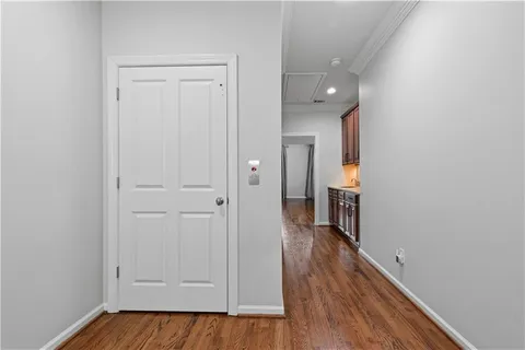 a view of a hallway with wooden floor and a bathroom