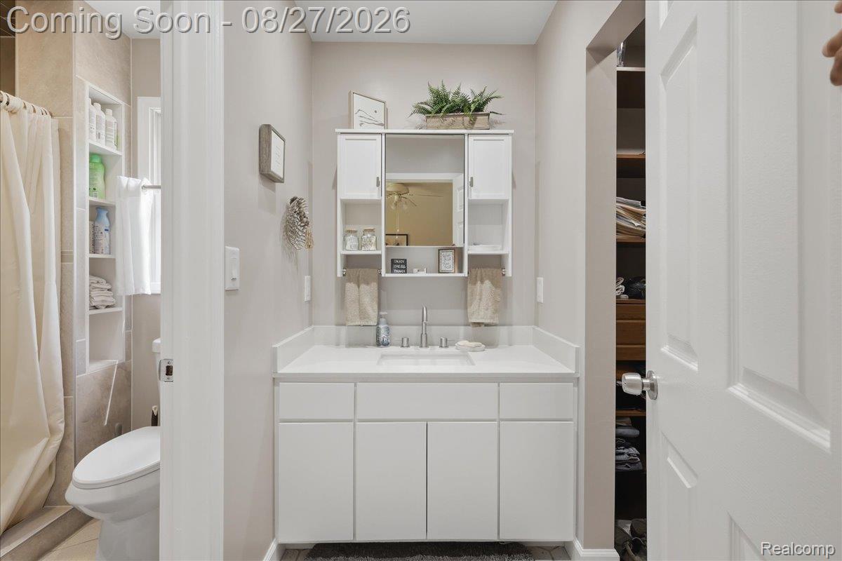 10100 Springtime Circle Clarkston, MI 48348 - Photo 35 of 73 White vanity with a single basin, wall-mounted medicine cabinet with mirror, and built-in shelving