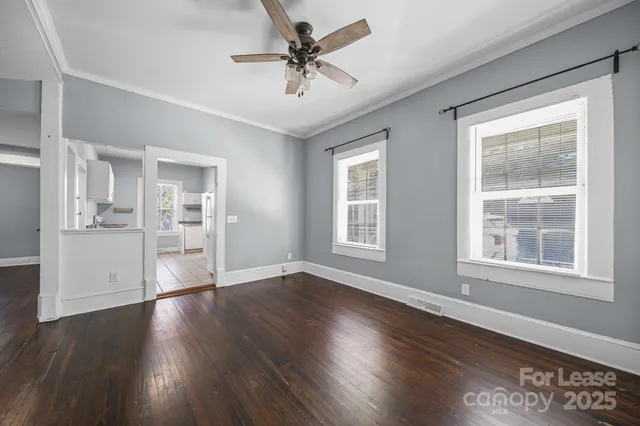 a view of an empty room with window and wooden floor