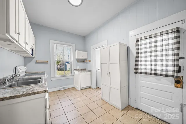 a kitchen with a refrigerator and white cabinets