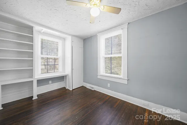 a view of an empty room with a window and wooden floor