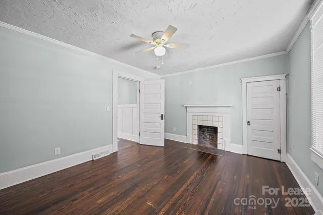 an empty room with wooden floor fireplace and windows
