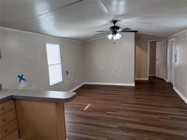 a view of an empty room with wooden floor and a ceiling fan