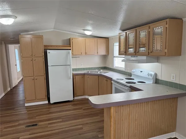a kitchen with a refrigerator a sink dishwasher and a stove with wooden floor