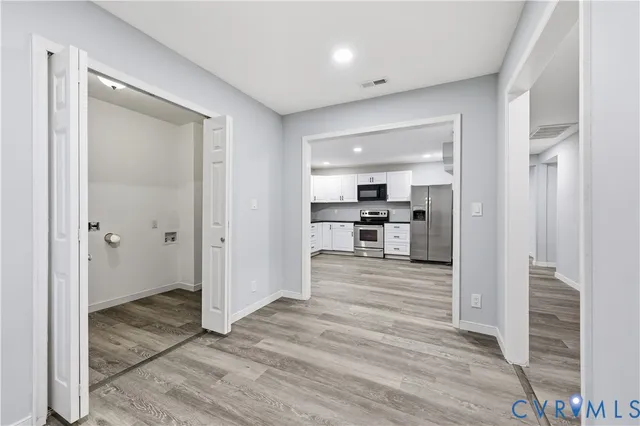 a view of a hallway with wooden floor and a living room