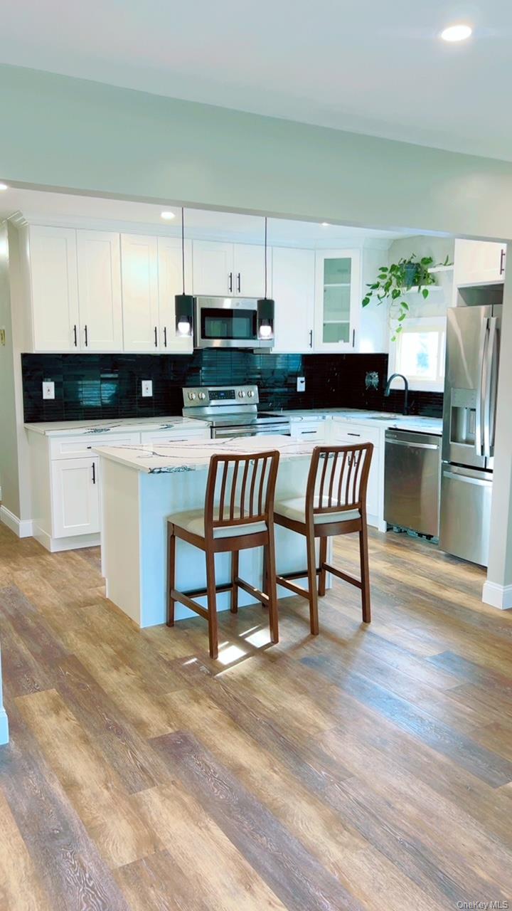 12 Terrace View Road Farmingdale, NY 11735 - Photo 7 of 21 a kitchen with stainless steel appliances kitchen island granite countertop a refrigerator a stove a sink and white cabinets with wooden floor