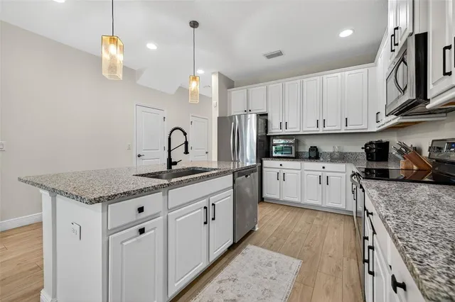 a kitchen with granite countertop a sink a counter space appliances and cabinets