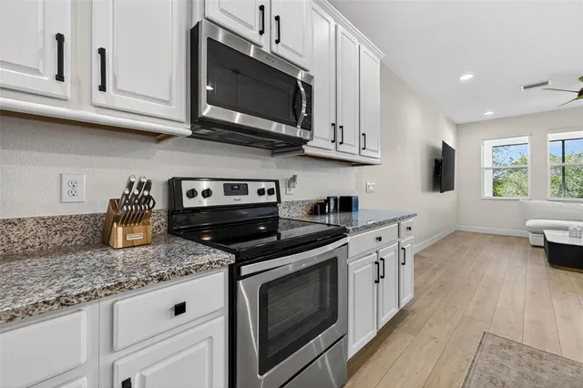 a kitchen with stainless steel appliances granite countertop white cabinets granite counter tops and a wooden floors