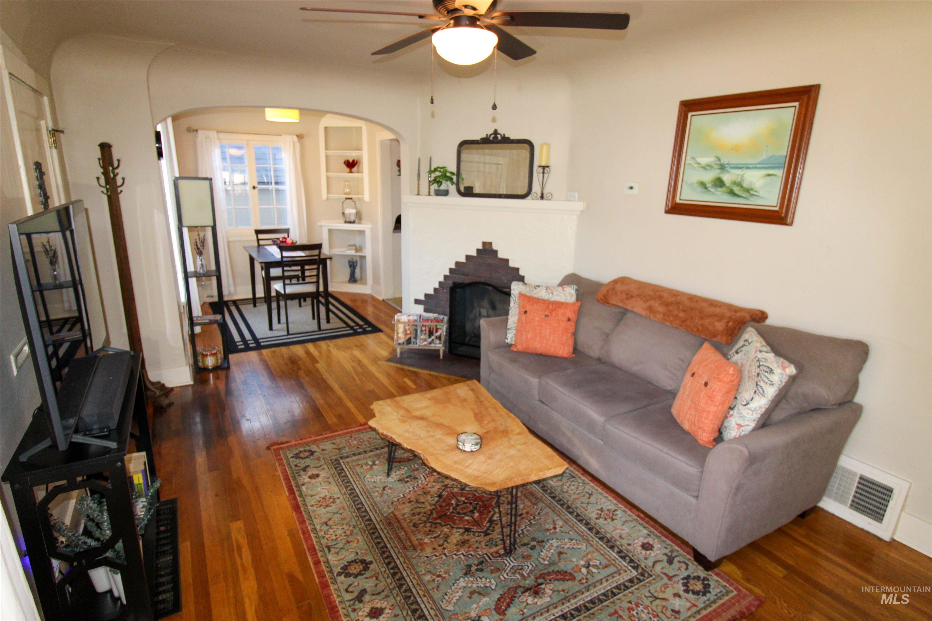 2551 West Hill Road Boise, ID 83702 - Photo 5 of 24 Living area with dark wood-type flooring, a ceiling fan, arched walkways, and a brick fireplace